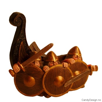 Tre vikinger i farver fremfor skipsstavnen uten horn